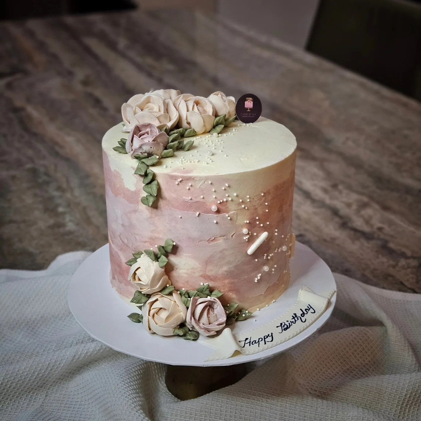 Blush cake with hand-piped flowers and delicate gold details